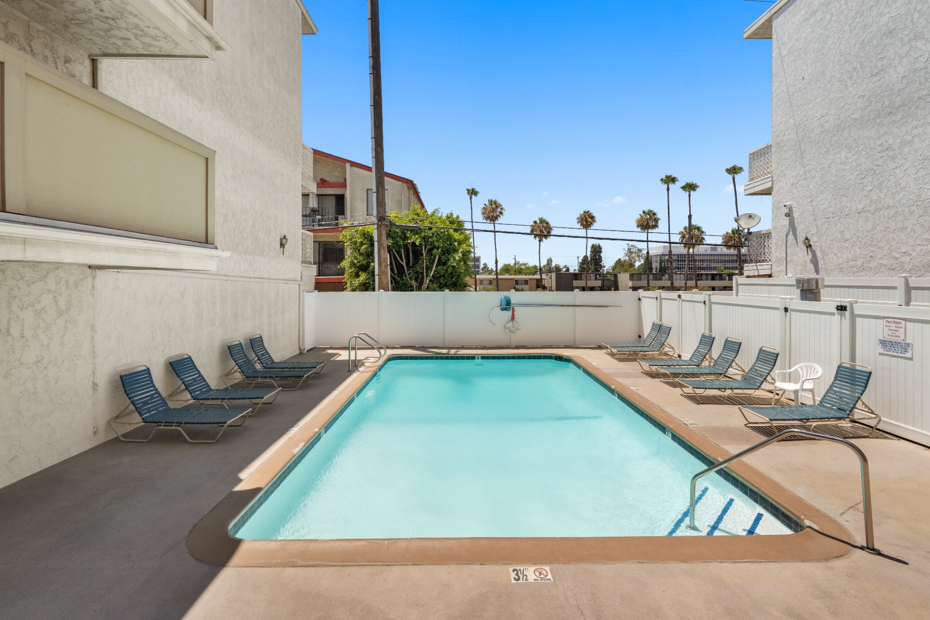 Sparkling community pool with lounge chairs and palm trees