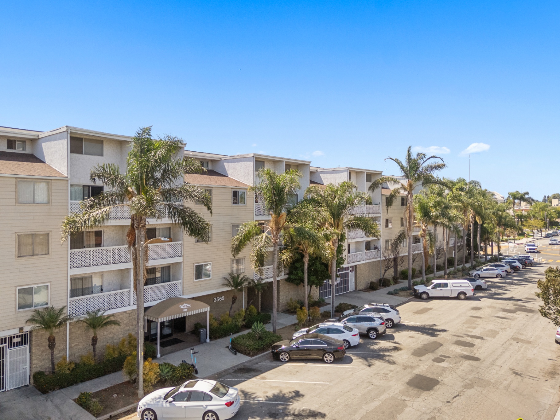 Aerial view along the palm-lined complex with balconies and parking