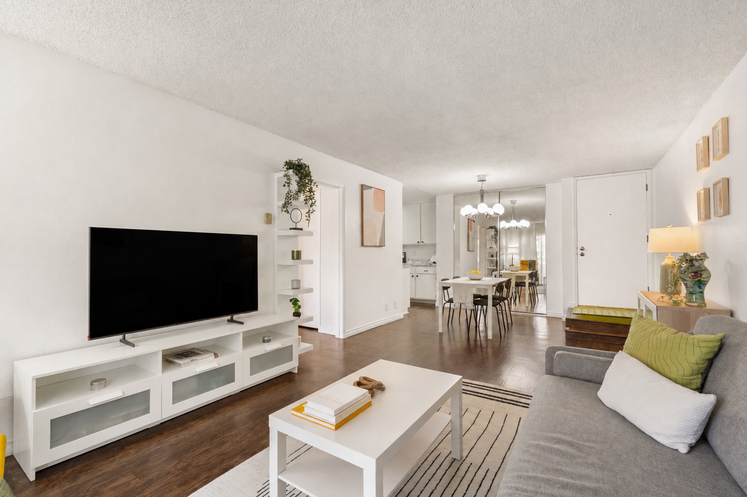 Living room with grey sofa, media console, and view back to the dining area