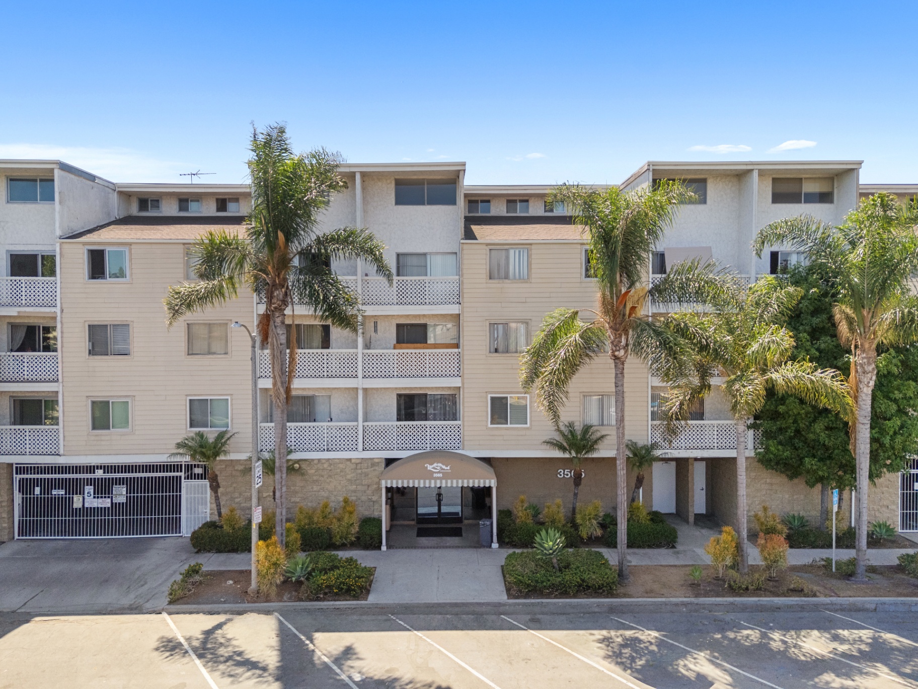 Front exterior of the gated Linden Ave complex with palm trees and covered entry