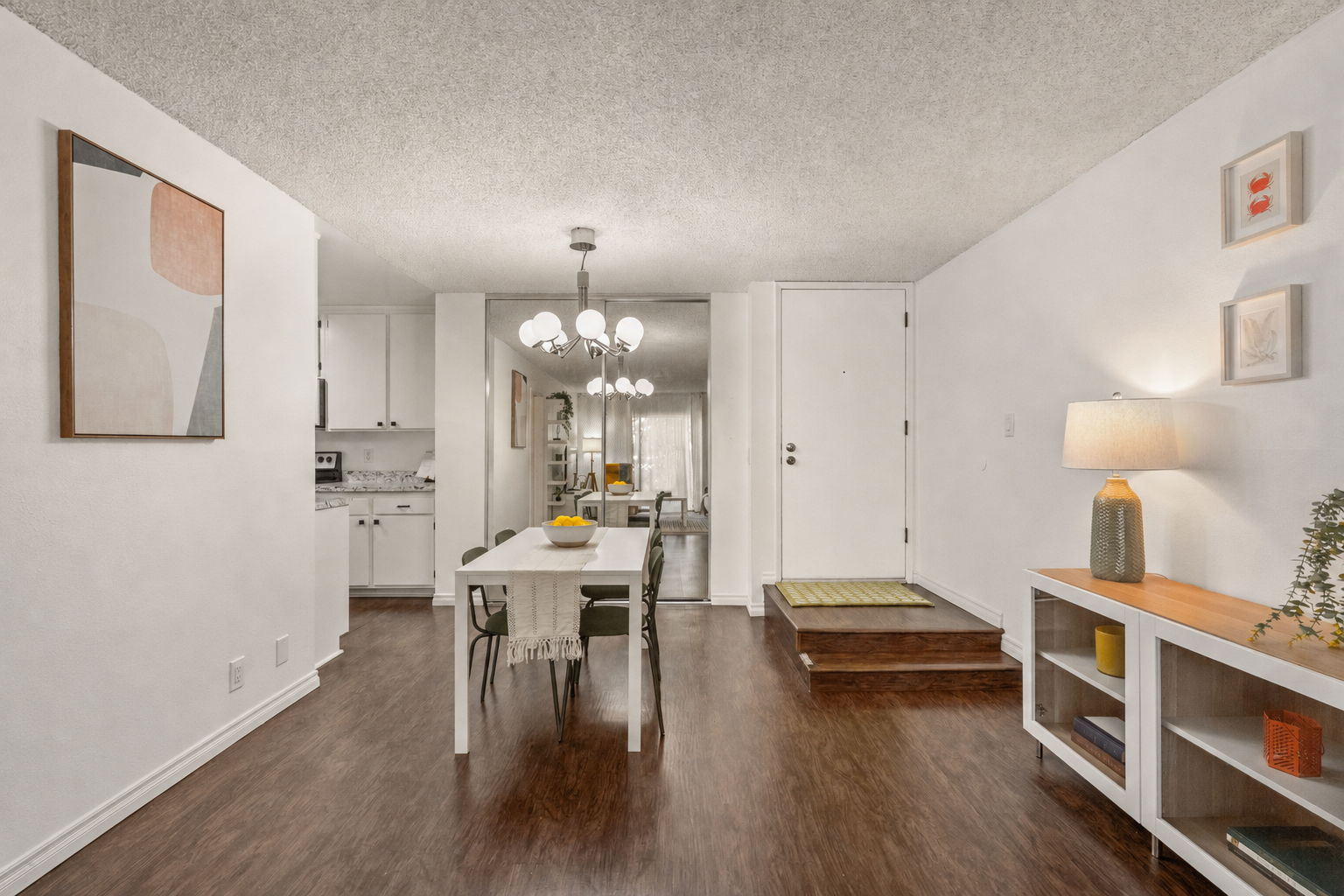 Wide entryway view showing the living/dining space with dining table and chandelier
